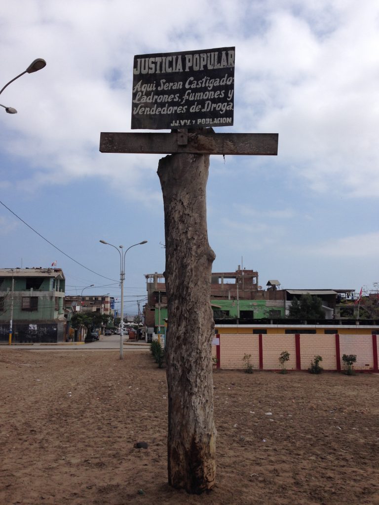 A sign on a cross located in Sector 2, Group 18 of the Villa El Salvador district in Lima warns, “Popular Justice: Thieves, Stoners, and Drug Dealers Will Be Punished Here.” Photo by Steven T. Zech.
